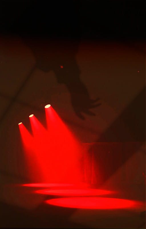 Black and red image of street lights and silhouette of hand